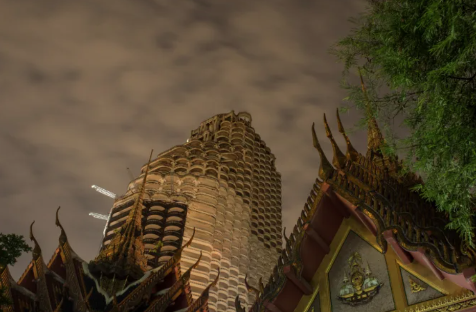 A partially constructed high-rise building with a cylindrical design stands tall under a cloudy night sky. In the foreground, the ornate roof of a traditional Thai temple is visible, with intricate, pointed decorations and carvings. The scene is surrounded by trees.