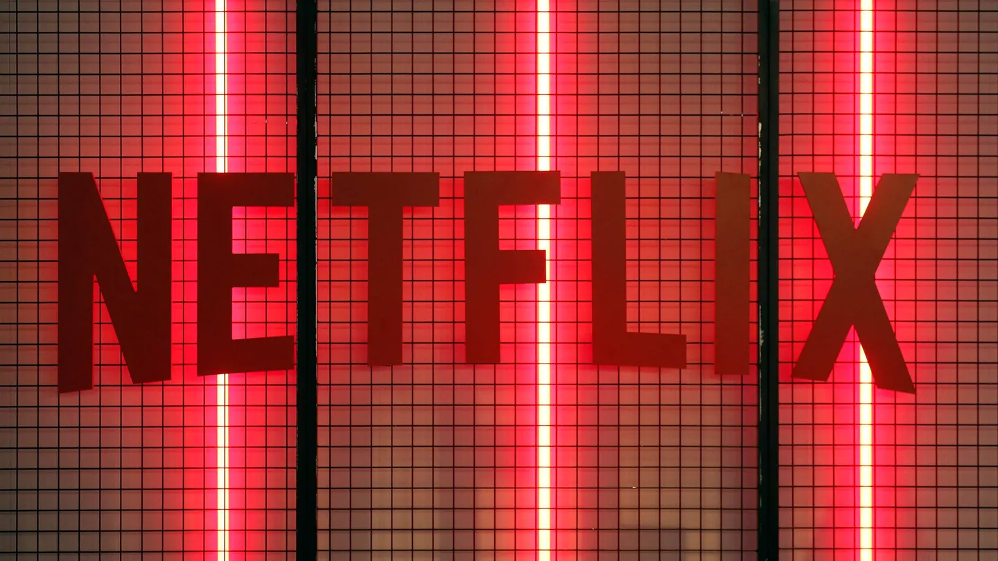 the word "NETFLIX" displayed in bold red letters against a black grid background, illuminated by red vertical neon lights