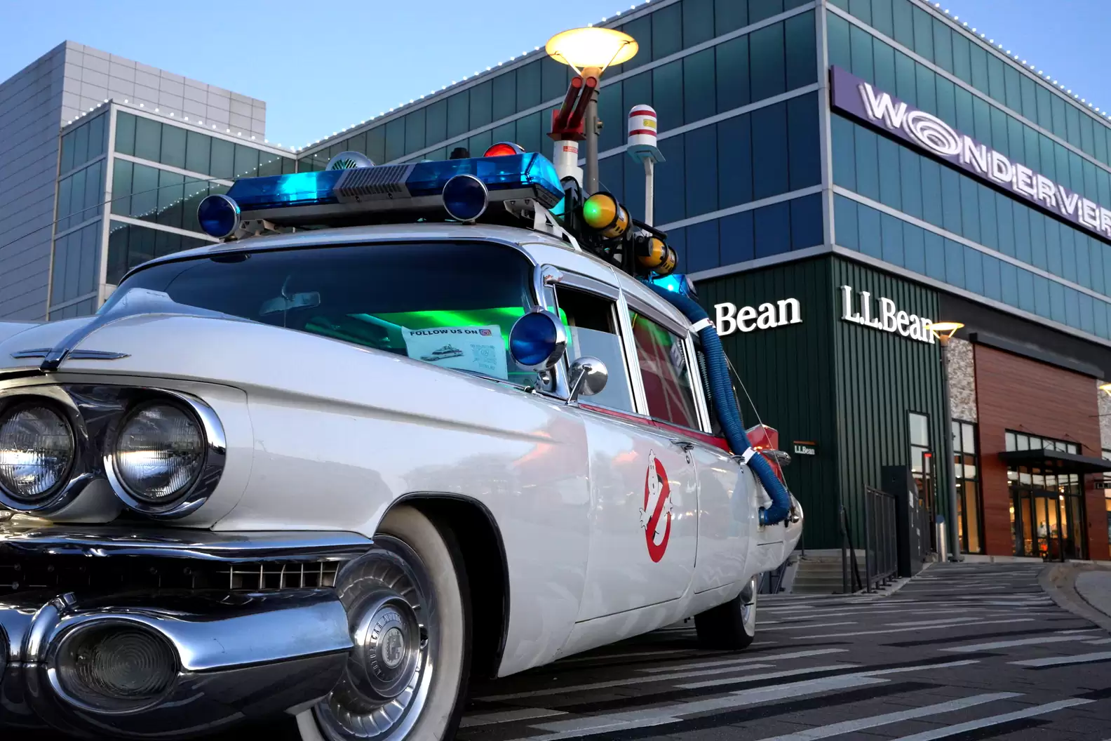 Ghostbusters white Ecto-1 car, featuring police lights and sirens, sitting in front of Wonderverse and L.L. Bean